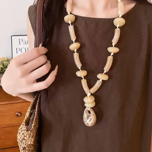 Detail view of long acrylic necklace with marbled oval pendant on beige cord