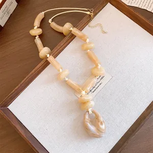 Detailed view of large marble-textured acrylic beads on a cream cord necklace