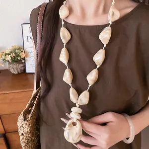 Close-up view of bohemian style acrylic oval bead necklace with cream marble finish texture