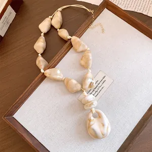 Detailed macro view of beige marble-textured acrylic beads on an adjustable cord necklace