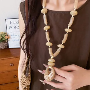 Close-up of beige marbled acrylic pendant necklace on model with vacation style vibe
