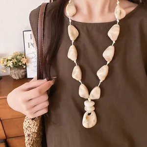 Detail of irregular cream acrylic bead necklace on a leather cord for vacation style.