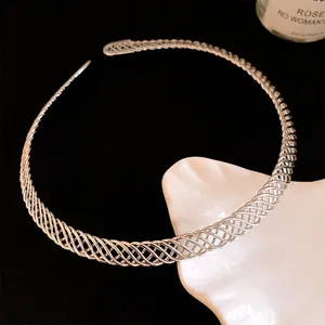 Gros plan d'un élégant collier ras de cou en métal tressé argenté sur coupelle blanche.