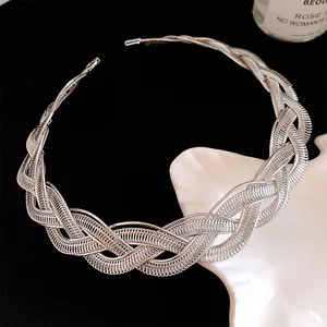 Détail d'un collier ras du cou en métal tressé argenté au design audacieux.