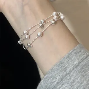 Dreilagiges Perlen- und Silberperlenarmband am Handgelenk für eleganten Modestil