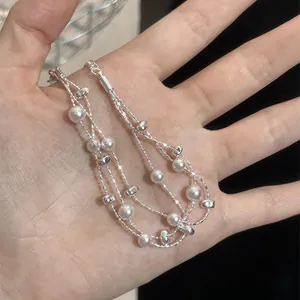 Detailansicht eines mehrlagigen Silberperlenarmbands mit eleganten weißen Perlen.
