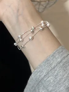 Detailansicht eines eleganten mehrlagigen Silberperlenarmbands mit rosa Perlen am Handgelenk