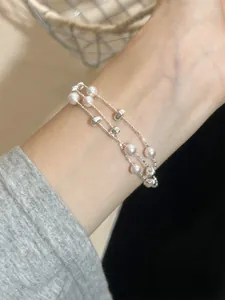 Nahaufnahme eines mehrlagigen Barockperlen-Armbands mit Silberperlen am Handgelenk