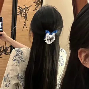 Detailed view of vintage blue butterfly hair clip with silver tassels on long dark hair