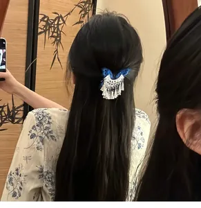 Close-up of an elegant vintage butterfly tassel hair clip worn on long wavy black hair.