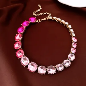 Makro-Detail einer Halskette mit rosa Kristallverlauf und Goldkette auf braunem Stoff