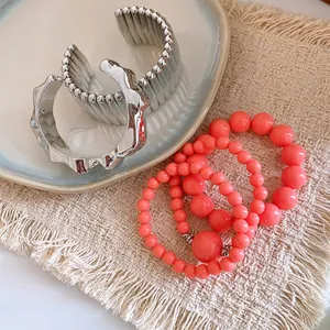 Close-up of Bohemian coral beaded bracelets and textured silver bangles on a woven mat
