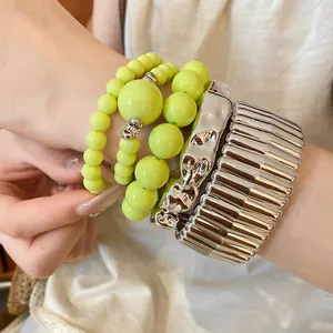 Detailed shot of vibrant yellow acrylic beaded bracelets and chunky silver cuffs set