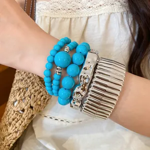 Bohemian style stacked bracelets featuring blue turquoise beads and wide silver metallic cuffs