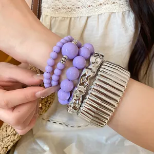 Detailed view of bohemian purple beaded bracelets and silver textured wide bangles set