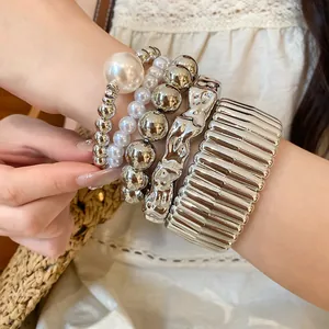 Close-up detail of stylish layered bohemian bracelets with pearls and metallic beads