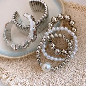 Close-up of Bohemian silver beaded bracelets and metallic bangles on a textured mat