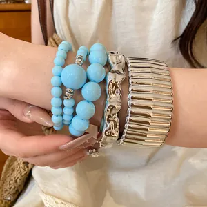 Detail of bohemian acrylic beaded bracelets and silver textured cuffs on wrist.