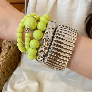 Detailed view of neon green acrylic beaded bracelets and textured silver metallic bangles