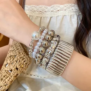 Close-up of layered bohemian metallic bangles and acrylic pearl beaded bracelets on wrist