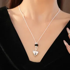 Élégant collier cœur argenté avec perles de pierre noire porté par un mannequin