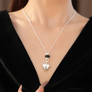Vue détaillée d'un collier en argent en forme de cœur avec perles noires.