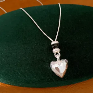 Gros plan détaillé d'un collier avec pendentif cœur mat facetté sur un support en velours