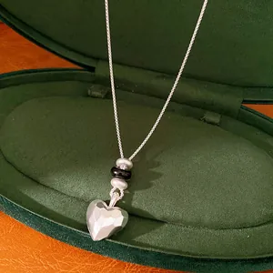 Vue rapprochée d'un collier en argent mat avec un pendentif coeur facetté et perles