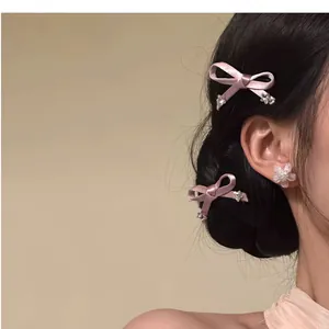 Side view of elegant pink bow hair clips with small flower details worn on dark hair.