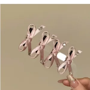 Close-up of four delicate pink silk ribbon bow hair clips with small rhinestone accents
