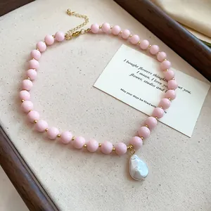 Detailed view of pink acrylic bead necklace featuring a white baroque pearl pendant.