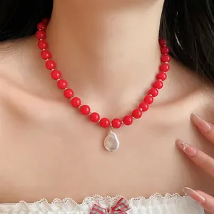 Detailed view of red acrylic bead necklace featuring a white baroque pearl pendant