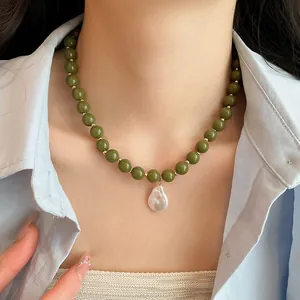 Close-up of olive green acrylic bead necklace with baroque pearl pendant on model