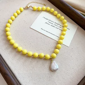Close-up of a vibrant yellow acrylic beaded necklace with a unique Baroque pearl pendant.