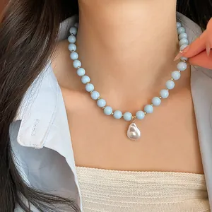 Close-up of a blue acrylic bead necklace featuring a white baroque pearl pendant detail.
