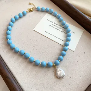 Macro view of light blue acrylic beaded necklace featuring a white baroque pearl pendant.