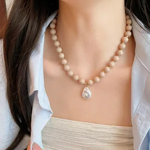 Model wearing view of acrylic bead necklace with a baroque pearl pendant detail.