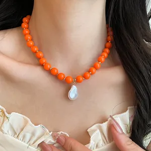 Detail view of orange acrylic bead necklace featuring a unique white baroque pearl pendant