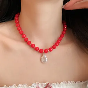 Detail view of red beaded necklace with white baroque pearl pendant on model