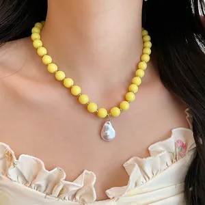 Close-up view of a yellow acrylic bead necklace featuring a baroque pearl pendant detail