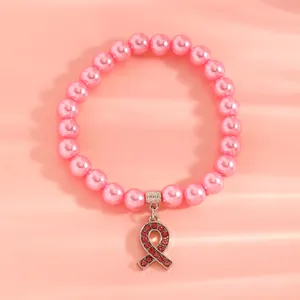 Close-up detail of the pink ribbon rhinestone pendant on the imitation pearl bracelet