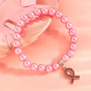 Close-up of pink imitation pearl bracelet with sparkling rhinestone pink ribbon charm