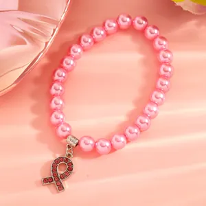 Vue rapprochée d'un pendentif ruban rose strass sur un élégant bracelet de perles.
