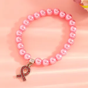 Close-up of pink imitation pearl bracelet with a sparkling rhinestone breast cancer ribbon charm.