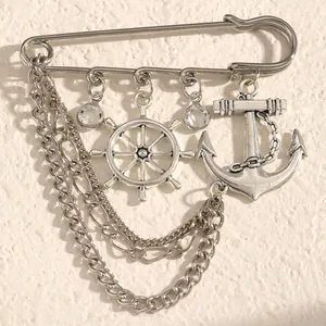 Detailaufnahme einer silbernen Seefahrt-Brosche mit Anker, Steuerrad und langen Ketten