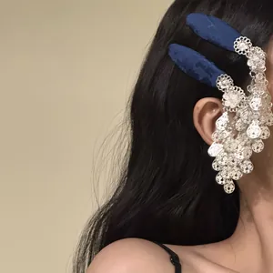 Detailed side view of silver filigree flower tassel hair clip with blue fabric texture