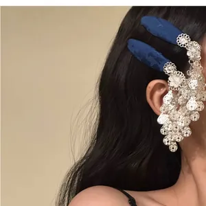 Macro view of an intricate silver floral tassel and dark blue fabric hair clip detail