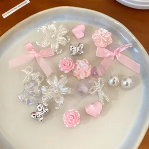 Assorted resin shoe charms featuring pink flowers, bows, and silver butterflies on a plate.