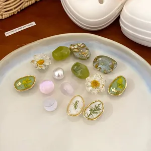 Detail showing various resin floral and stone-patterned shoe charms on a plate.