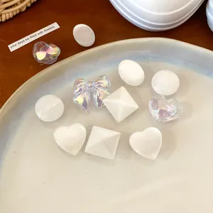 Close-up of pearlescent white and holographic resin shoe charms in various cute shapes.